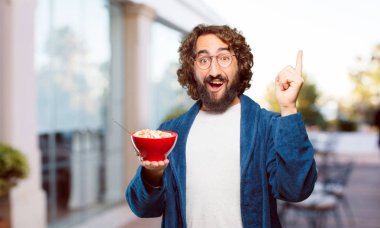 Bornoz giyip kahvaltı kasesi takan genç bir adam.