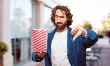 Bornoz giyip, üzerinde patlamış mısır kovası olan genç adam.