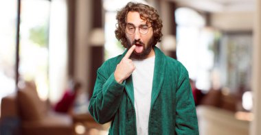 Bornoz giyen genç adam kızgın ve üzgün.