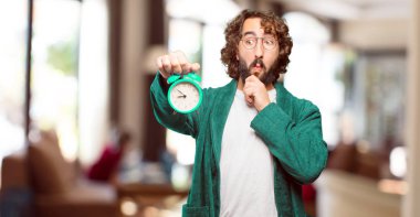 Çalar saati olan bornoz giymiş genç bir adam.