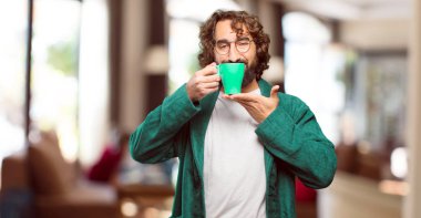 Bornoz giyen genç adam kahve içiyor.