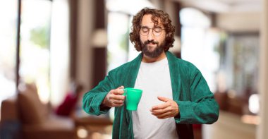 Bornoz giyen genç adam kahve içiyor.