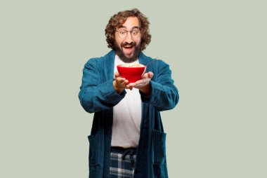 Bornoz giyip kahvaltı kasesi takan genç bir adam.