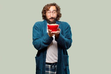 Bornoz giyip kahvaltı kasesi takan genç bir adam.