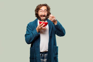 Bornoz giyip kahvaltı kasesi takan genç bir adam.