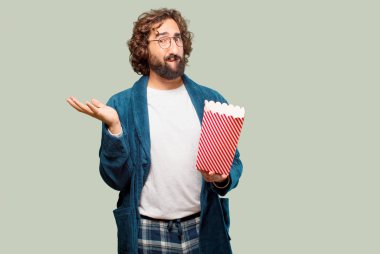 Bornoz giyip, üzerinde patlamış mısır kovası olan genç adam.