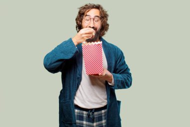 Bornoz giyip, üzerinde patlamış mısır kovası olan genç adam.