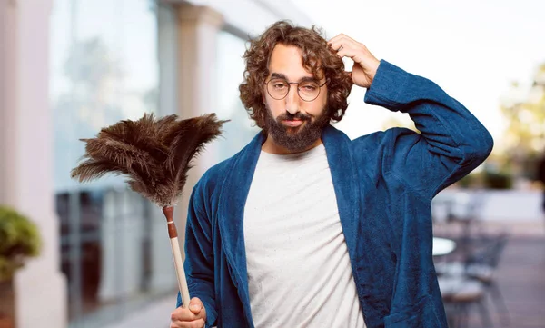 Bornoz giyip, toz bezi giyen genç adam.