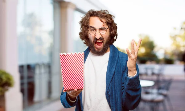 Bornoz giyip, üzerinde patlamış mısır kovası olan genç adam.