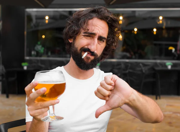 young bearded man smoking and drinking a beer