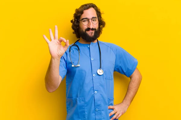 young nurse man with okay gesture against yellow background