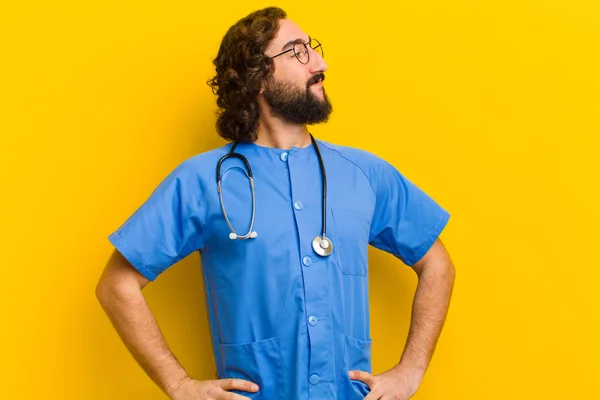 Jovem enfermeira homem pensando contra fundo amarelo — Fotografia de Stock