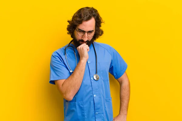 Jonge verpleegster man denken tegen gele achtergrond — Stockfoto