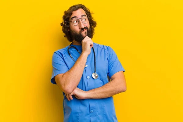 Jonge verpleegster man denken tegen gele achtergrond — Stockfoto