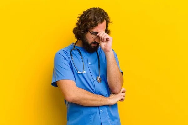 Junger Krankenpfleger denkt vor gelbem Hintergrund — Stockfoto