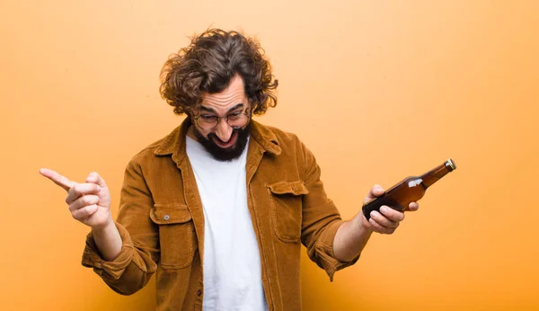 Nuori mies hullu tukka liikkeessä juo olutta — kuvapankkivalokuva