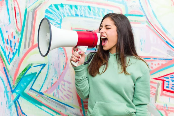 young pretty woman with a megaphone against graffiti wall