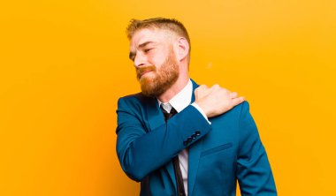 genç kırmızı kafa işadamı duygu yorgun, stresli, endişeli, sinirli ve depresif, turuncu arka plan karşı sırt veya boyun ağrısı ile acı