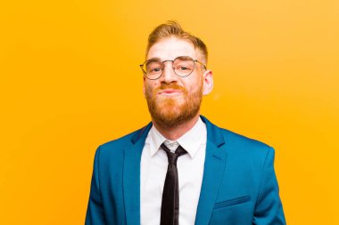 genç kırmızı kafa işadamı birlikte sevimli, eğlenceli, mutlu, güzel ifade ile dudakları basarak, turuncu arka plan karşı bir öpücük gönderme