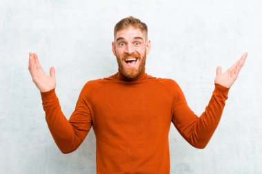 genç kırmızı baş adam kaplumbağa boyun giyen şok duygu ve heyecanlı, gülerek, şaşırmış ve mutlu çimento duvara karşı beklenmedik bir sürpriz nedeniyle