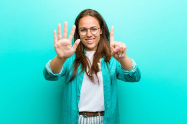 genç kadın gülümseyen ve samimi görünümlü, el ileri ile altı veya altıncı numara gösteren, mavi arka plan karşı geri sayım