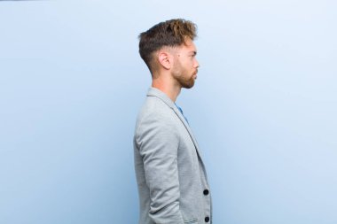 profil görünümünde genç işadamı, mavi arka plan karşı düşünme, hayal veya hayal ileride alan kopyalamak isteyen