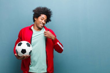 Genç siyah bir adam futbol topuyla mavi grunge wa 'ya karşı.