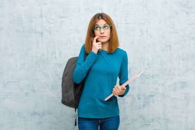 Şaşırmış, gergin, endişeli ya da korkmuş bakışları olan genç bir kadın grunge duvarına karşı fotokopi odasına bakıyor.