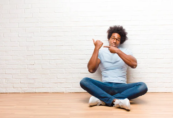 年轻的黑人男子看起来不耐烦和愤怒 指着手表 要求准时 想准时坐在地板上在家里 — 图库照片