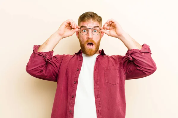 Jovem Homem Cabeça Vermelha Sentindo Chocado Surpreso Surpreso Segurando Óculos — Fotografia de Stock