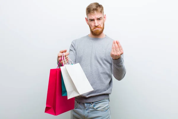 Junger Roter Mann Mit Einkaufstüten Vor Weißem Hintergrund — Stockfoto