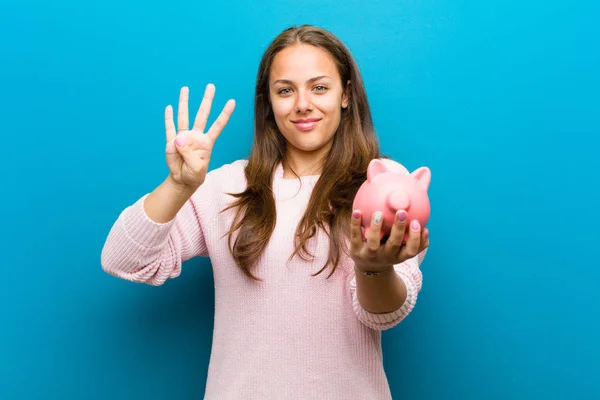 Jonge vrouw met een Piggy Bank tegen blauwe achtergrond — Stockfoto