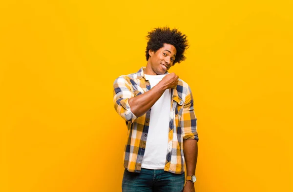 年轻的黑人男子看上去骄傲自满 积极向上 直指橙色的墙 — 图库照片