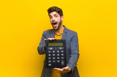 Turuncu arka planda hesap makinesi olan genç yakışıklı bir adam.