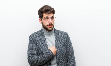 Genç yönetici kendini şaşkın, şaşkın ve güvensiz hissediyor. Kendini merak edip bana mı soruyor? Beyaz duvara yaslan