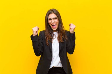 Genç, güzel bir kadın mutlu, pozitif ve başarılı hissediyor, zaferi kutluyor, başarılar ya da turuncu duvara karşı iyi şanslar diliyor.