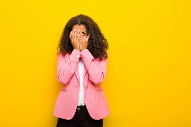 Siyah iş kadını korkmuş ya da utanmış hissediyor, gözleri yarı kapalı turuncu duvara bakıyor ya da dikizliyor.