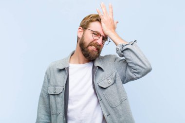 Genç sarışın yetişkin bir adam, aptalca bir hata yaptıktan ya da hatırladıktan sonra, kendini aptal gibi hissederek avuçlarını kaldırıyor.