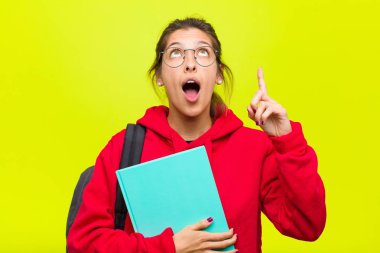 Genç ve güzel bir öğrenci şaşırmış, şaşırmış ve ağzı açık bir şekilde iki elini de havaya kaldırıp boşluğu dolduruyor.