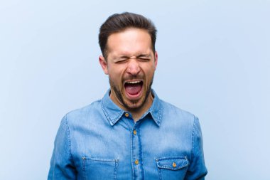 Genç yakışıklı adam agresif bir şekilde bağırıyor, çok kızgın, hayal kırıklığına uğramış, öfkeli ya da sinirli görünüyor, hayır