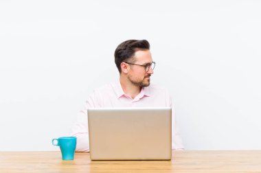 Profil görünümlü genç yakışıklı iş adamı ilerideki boşluğu kopyalamaya çalışıyor, düşünüyor, hayal ediyor ya da hayal kuruyor.