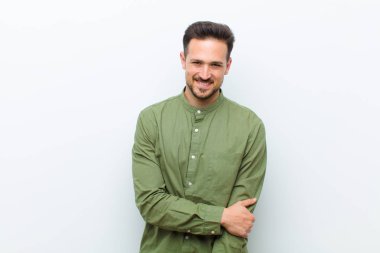 Genç yakışıklı adam utangaç ve neşeli bir şekilde gülüyor, arkadaş canlısı ve olumlu ama güvensiz bir tavırla.