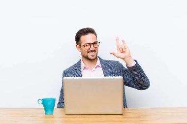 Genç yakışıklı iş adamı kendini mutlu, eğlenceli, kendinden emin, pozitif ve asi hissederek elle rock veya heavy metal işareti yapıyor.