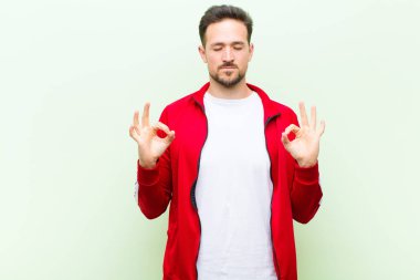 Genç yakışıklı sporcu ya da monitör odaklanmış ve meditasyon yapıyor, tatmin oluyor ve rahatlıyor, düşünüyor ya da düz duvara karşı bir seçim yapıyor.