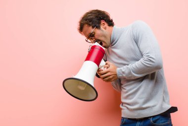 Pembe düz duvara karşı megafonlu genç yakışıklı adam.