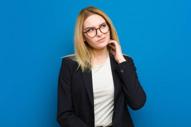 Genç, güzel, sarışın bir kadın stresli ve hayal kırıklığına uğramış hissediyor. Yumruk yumruğa, yorgun, mutsuz ve migreni düz duvara dayanmış.