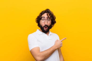 Genç çılgın adam heyecanlı ve şaşırmış görünüyor. Yana ve yukarıya bakıyor. Sarı duvara uzayı kopyalamak için.