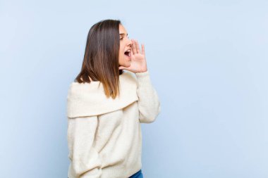 Genç ve güzel bir kadının profil görüntüsü, mutlu ve heyecanlı görünüyor, bağırıyor ve mavi arka planda yer almak için çağırıyor.