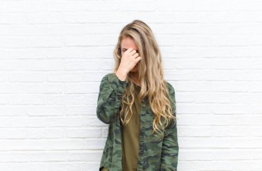 Genç sarışın kadın stresli, mutsuz ve hayal kırıklığına uğramış, alnına dokunmuş ve şiddetli baş ağrısı çekiyor.