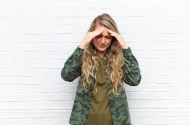 Genç sarışın kadın stresli ve hayal kırıklığına uğramış görünüyor. Baskı altında çalışıyor. Başı ağrıyor.